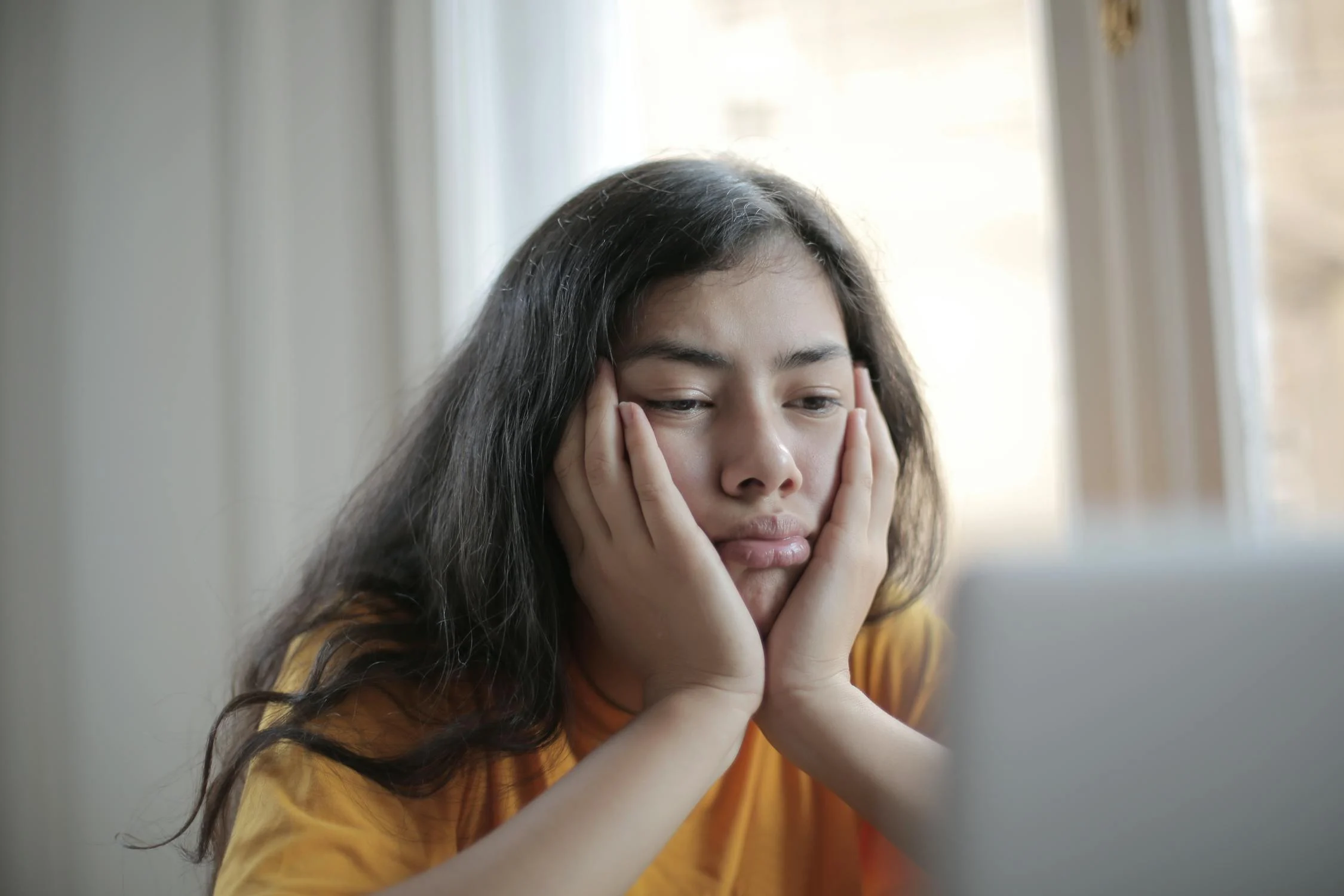 Melancholic woman looking at laptop screen